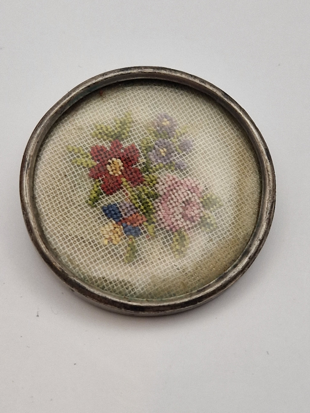 Antikk brosje i 925 sølv med brodert blomsterdekor under plastlokk