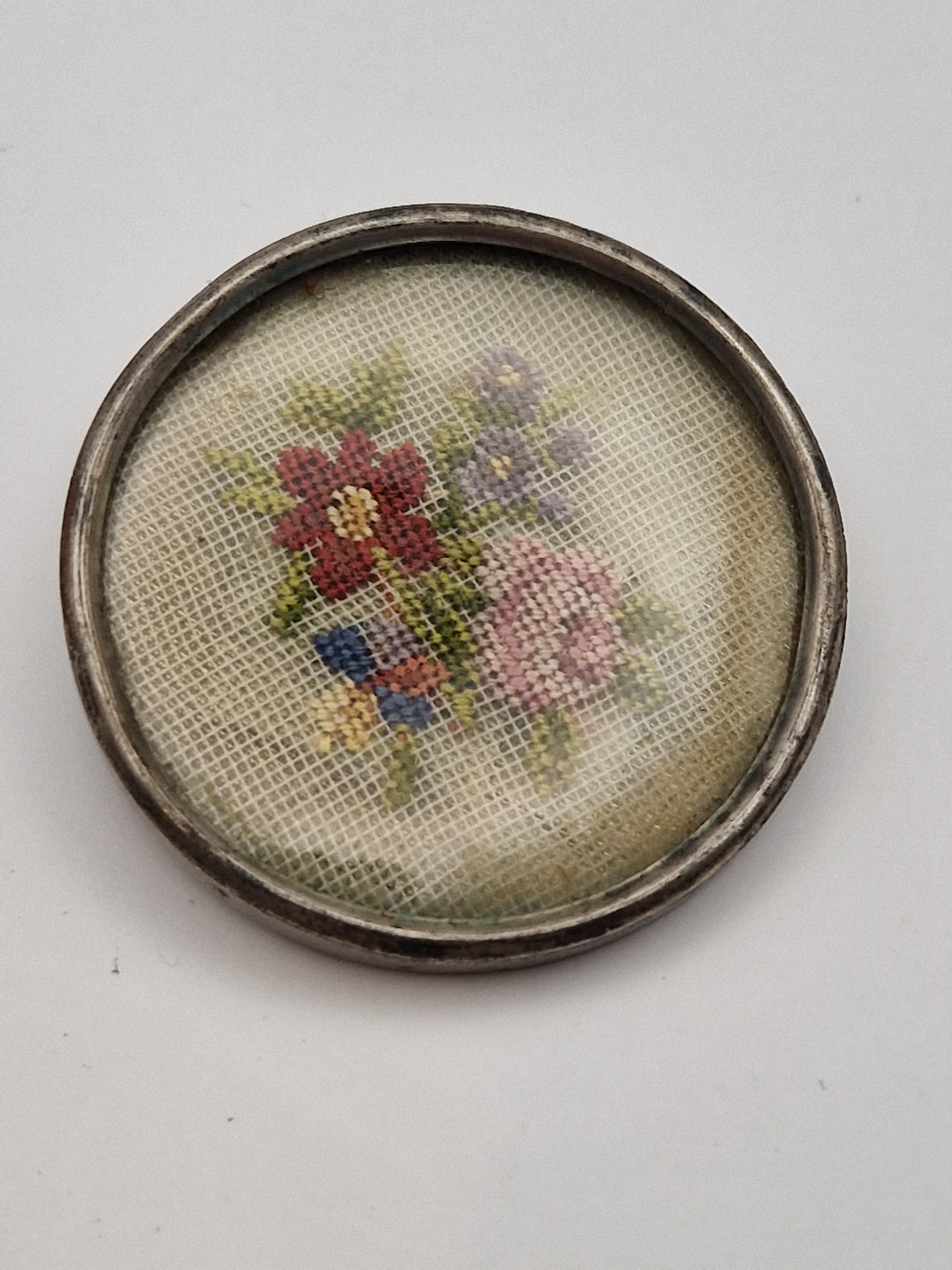Antikk brosje i 925 sølv med brodert blomsterdekor under plastlokk