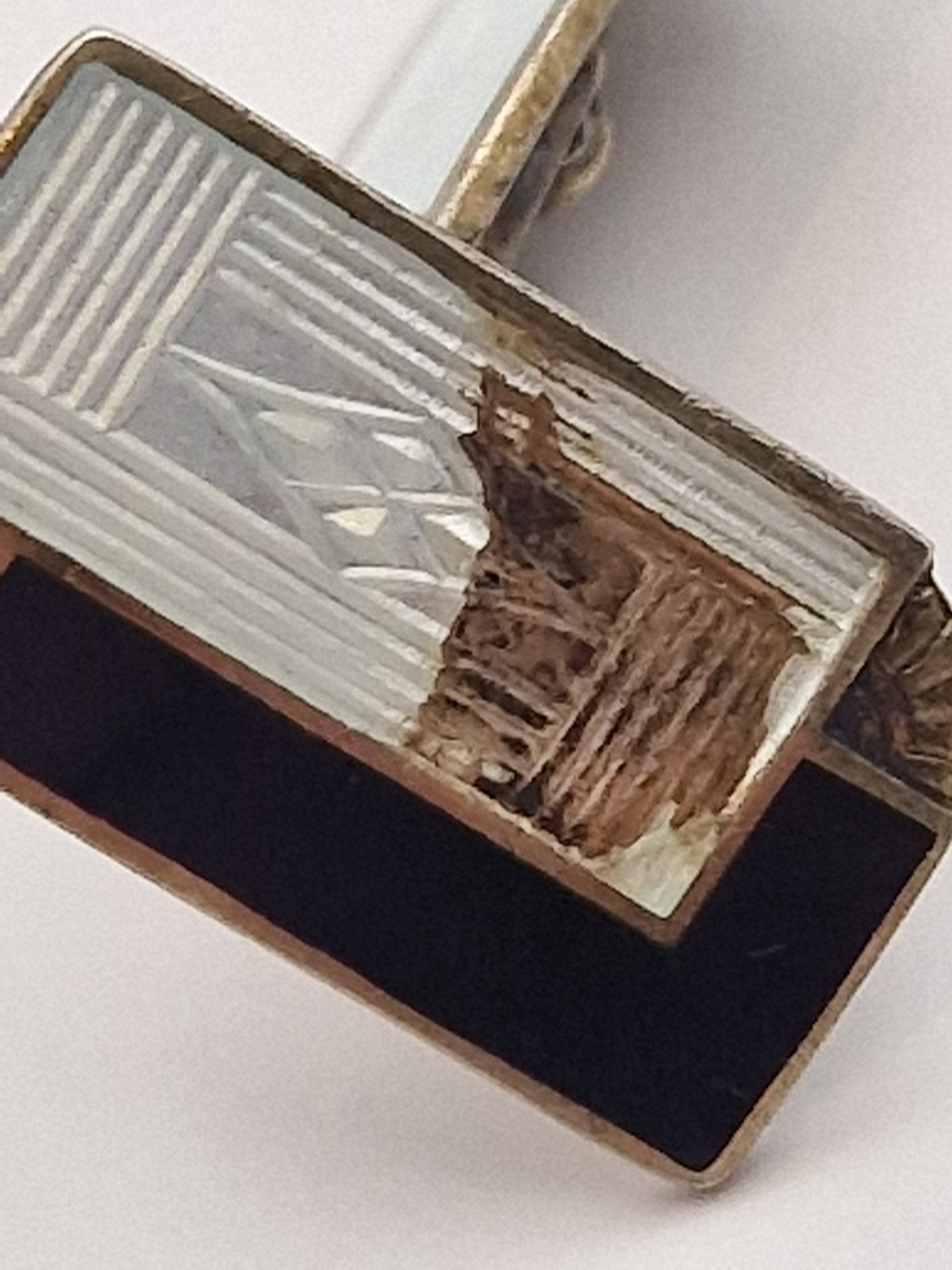 Nærbilde av emaljeskade på vintage mansjettknapper